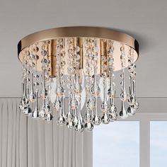 a chandelier hanging from the ceiling in a living room with white walls and curtains