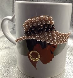 a coffee cup with beaded hair on it and a ring in the middle is sitting on a table