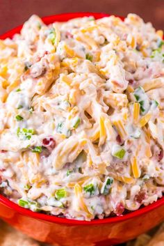 a red bowl filled with macaroni salad on top of tortilla chips