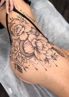 a woman's thigh with flowers on it and an arrow tattoo in the middle