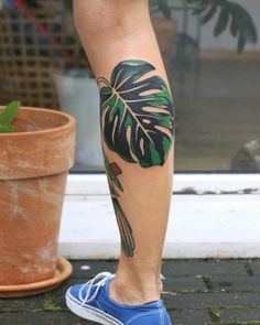 a person's leg with a tattoo on it and a plant in the background