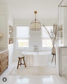 a bathroom with a large white bathtub and wooden stools