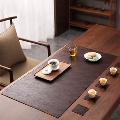 a wooden table topped with two plates of food next to tea cups and saucers