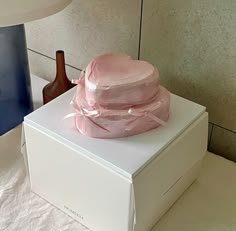 a pink hat sitting on top of a white box