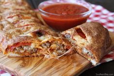 some food is laying on a cutting board with a bowl of sauce in the background