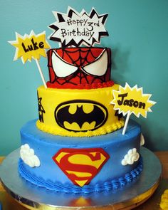 a three tiered cake decorated with batman and spiderman decorations