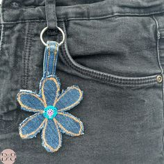 a blue flower keychain hanging from the back pocket of a pair of jeans