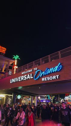 the entrance to universal resort at night with people walking around and onlookers