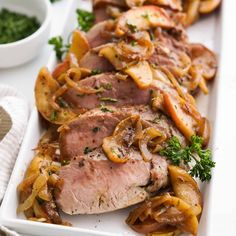 meat with onions and mushrooms on a white platter