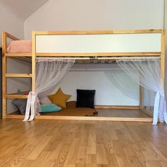 a bunk bed with mosquito netting on the top and bottom, in a room with hard wood flooring