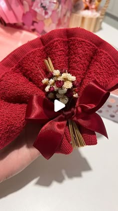 a hand holding a red towel with flowers in it