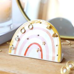 a white and gold plate with a rainbow design on the front sitting on a wooden table