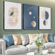 three paintings hang on the wall above a white couch in a living room with blue and gold accents