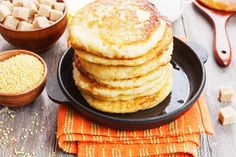 a stack of pancakes sitting on top of a black plate next to bowls of cereal