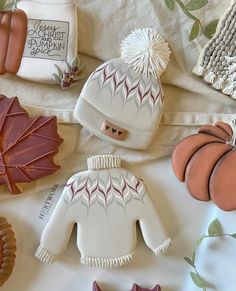 some cookies are laying on a table with hats and sweaters around them, as well as pumpkins