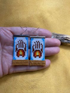 a pair of handmade beaded earrings in the shape of an animal's paw