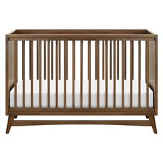 a wooden crib with white sheets on it