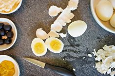 an assortment of eggs, black olives and other ingredients on a granite counter top