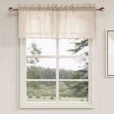 a window with a white curtain hanging from it's side in front of a painting on the wall