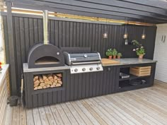 an outdoor bbq with wood logs and potted plants on the outside deck area