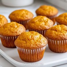 several muffins on a white plate sitting on a table