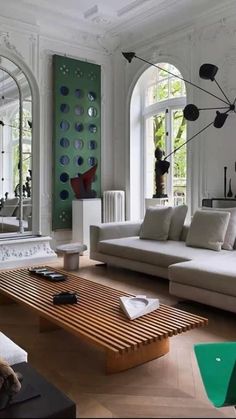 a living room filled with lots of furniture and large mirrors on the wall above it