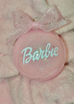 a pink ball with the word barbie painted on it and a bow around its neck