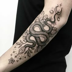 a woman's arm with a snake and flowers tattoo design on the left forearm