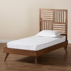 a wooden bed frame with white pillows on top of it and wood flooring in the background