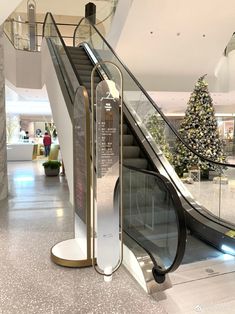 an escalator in a shopping mall next to a christmas tree