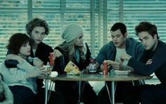 four people sitting around a table eating food