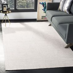 a living room with a gray couch and white rug on the floor in front of a window