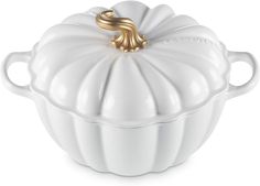 a white pumpkin shaped dish with gold accents on the top and bottom, sitting in front of a white background