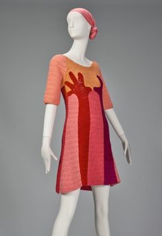 a white mannequin wearing a pink and orange knitted dress with an openwork design