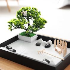 a small bonsai tree in a tray with rocks and stones on the table next to it