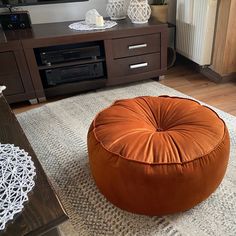 a living room with a large round ottoman on the floor and a flat screen tv