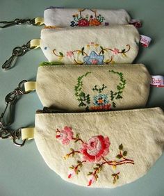 three purses with embroidered flowers on them are sitting next to each other and one has a keychain