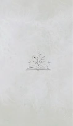 an open book sitting on top of a table next to a flower vase with flowers growing out of it