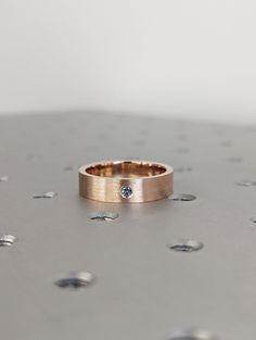 a gold ring with a blue diamond sits on top of a silver table covered in confetti