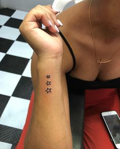 a woman's arm with three stars on it and a phone in the background