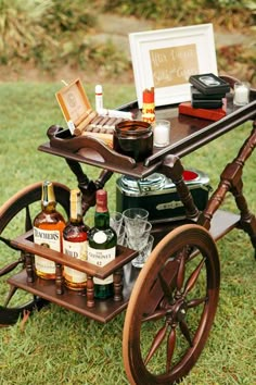 an old fashioned bar cart filled with liquor bottles and wine glasses on top of green grass