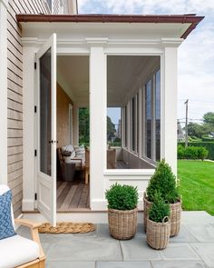 two planters sitting on the front porch of a house with an open patio door