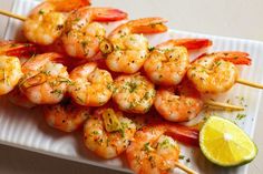 shrimp skewers with lemon wedges on a white plate