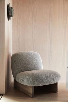 a gray chair sitting in front of a wooden wall next to a white refrigerator freezer