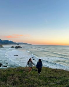 two people walking along the coast at sunset