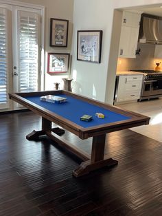 a pool table in the middle of a room with pictures on the wall behind it