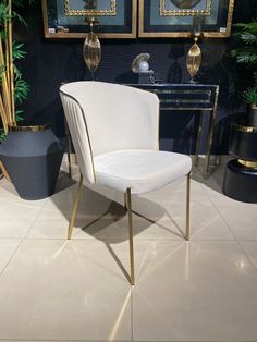 a white chair sitting on top of a tile floor next to a potted plant