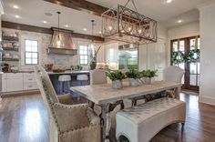 a large dining room table and chairs in front of an open kitchen area with wood floors