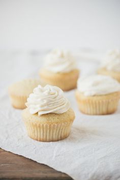 three cupcakes with white frosting sitting on top of a paper towel next to each other