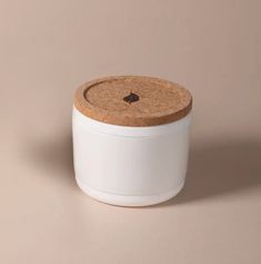 a white container with a cork lid on a beige background, it's empty